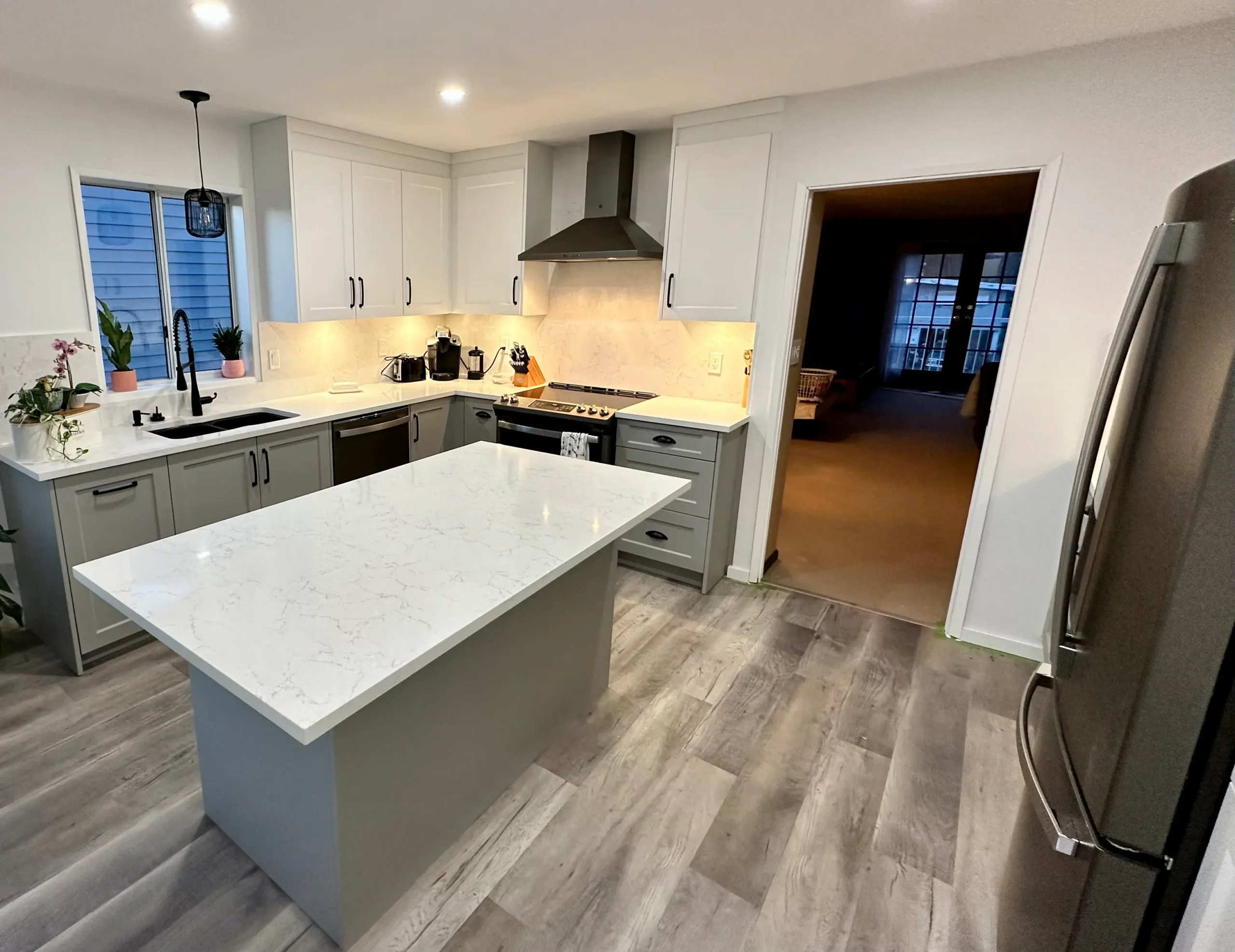 Mid-range Calgary kitchen renovation with quartz island, two-tone cabinets, updated flooring, and modern lighting